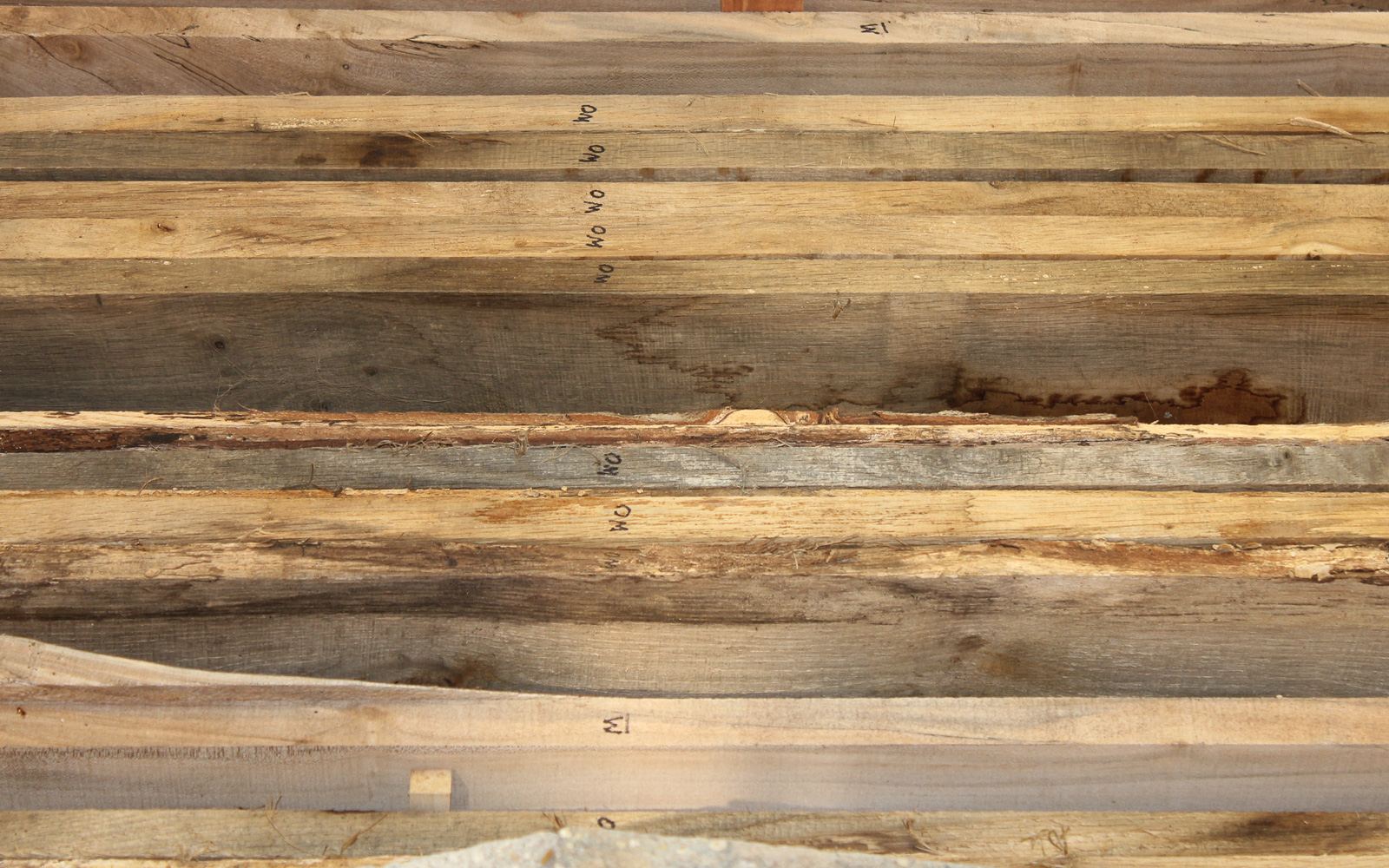 Rough-sawn boards stacked and stickered for air drying, each marked for grade