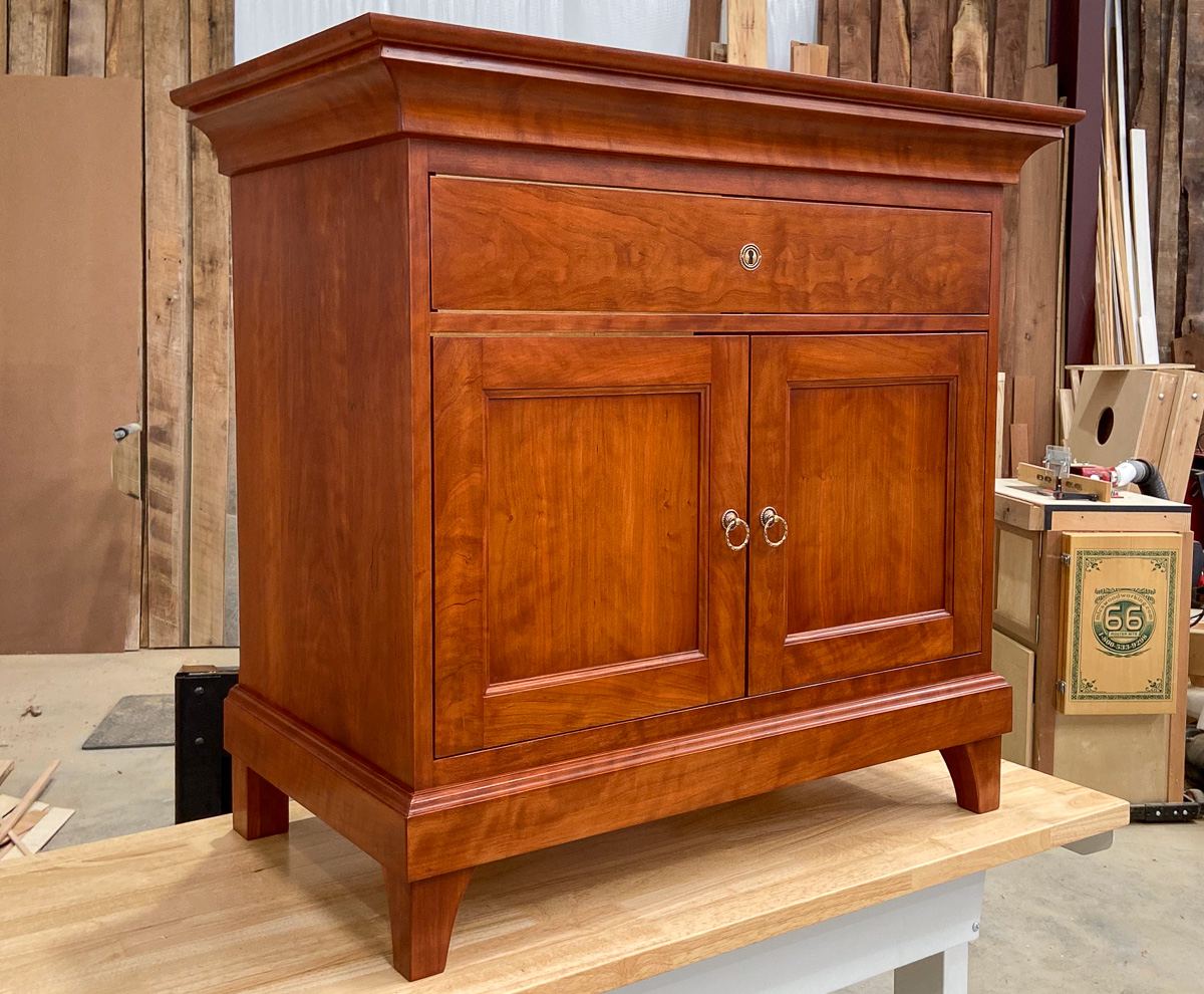The finished cherry vanity built from the drawing, with inset paneled doors, a locking top drawer and shaped feet