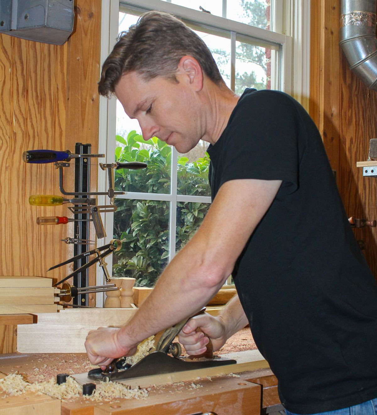 Erin Watson smoothing a board with a hand plane at the workbench
