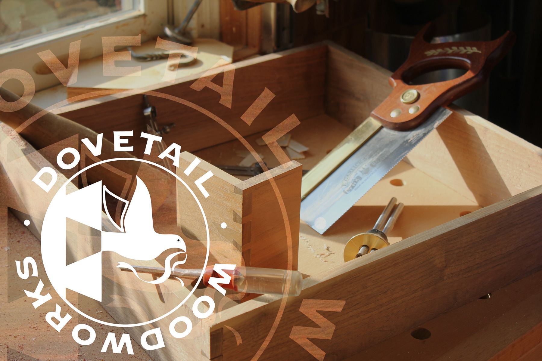 A hand-cut dovetailed drawer box on the bench with a dovetail saw, chisel and marking gauge